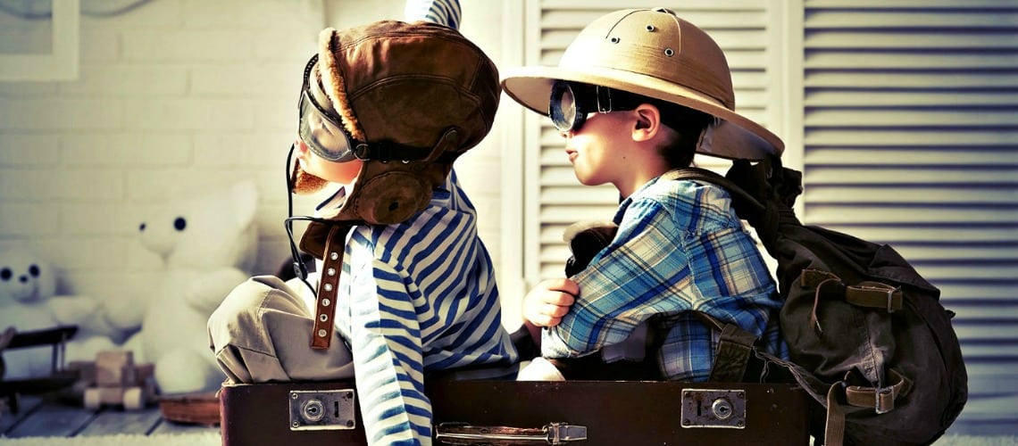 Deux petits garçons assis dans une valise jouent les aviateurs et les aventuriers en sac à dos