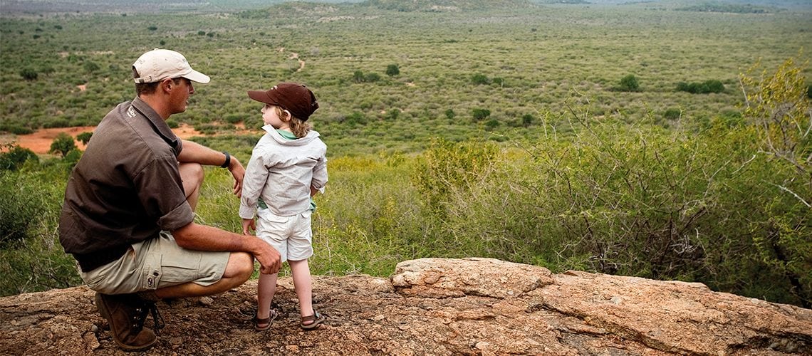 un homme et un enfant dans la nature (Afrique) couverts contre les moustiques