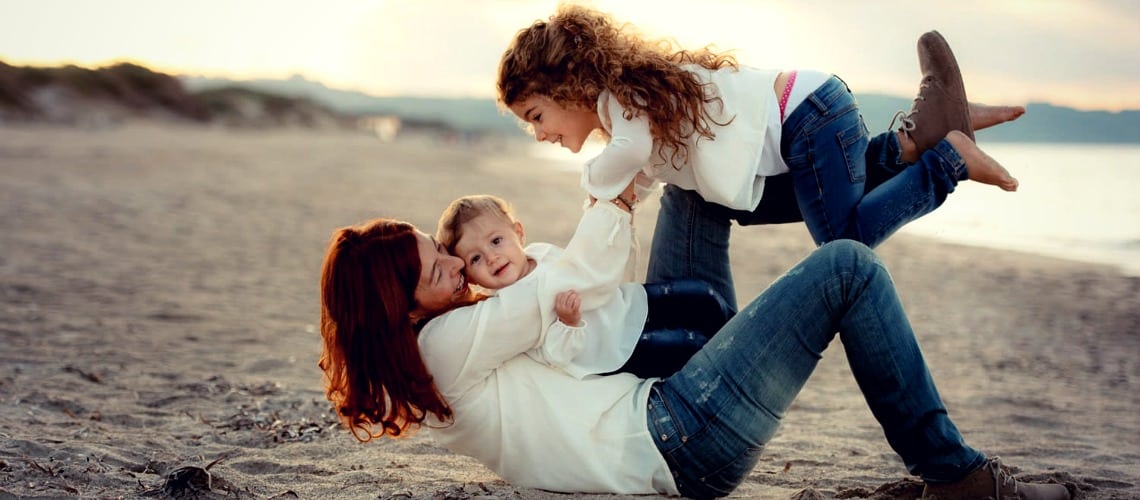 Une maman joue avec ses deux enfants sur une plage d'Alicante