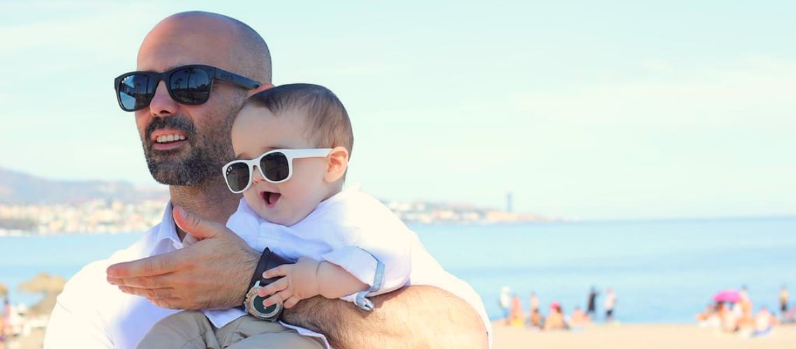 Father and baby on the beach wearing sunglasses