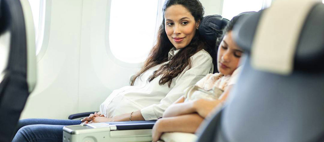 A future mum looks at her sleeping kid on an airplane