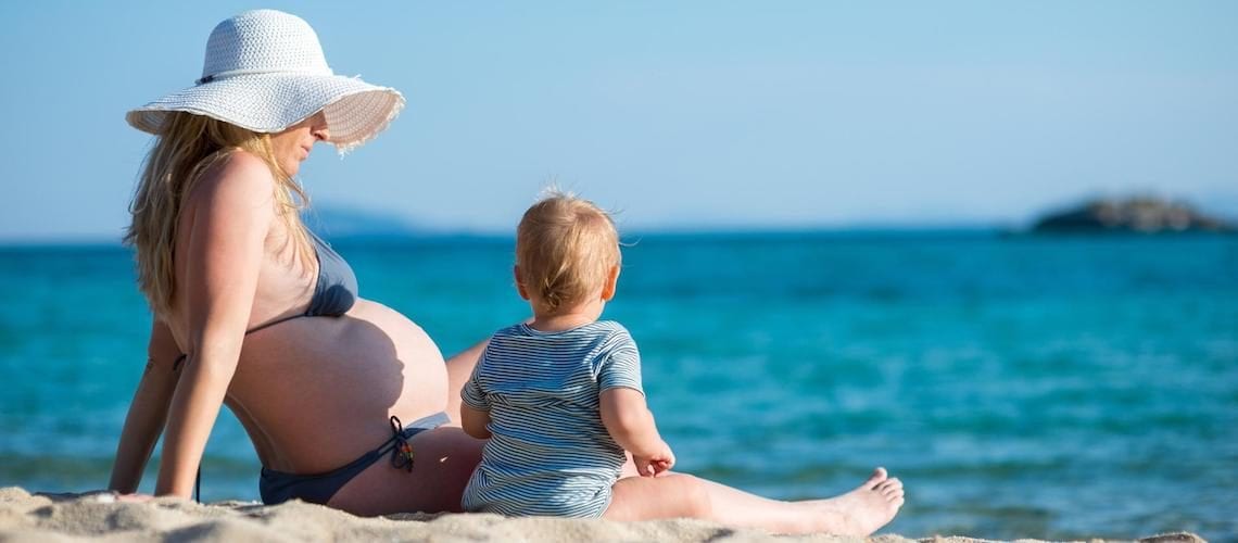 femme-enceinte-et-son-bébé-assis-sur-la-plage