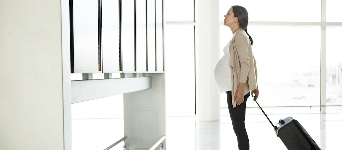 femme-enceinte-regarde-panneau-affichage-aéroport