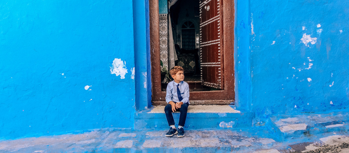 A little boy sitting in one of the Chefchaouen street in Morocco