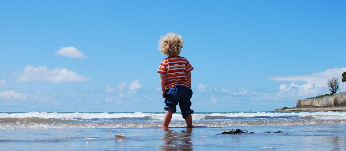 A child walking on the beach and catching the waves