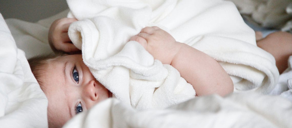 baby-smiles-white-sheets