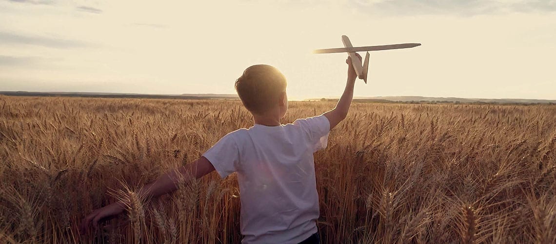 enfant-dans-un-champ-de-blé-jouant-avec-un-avion