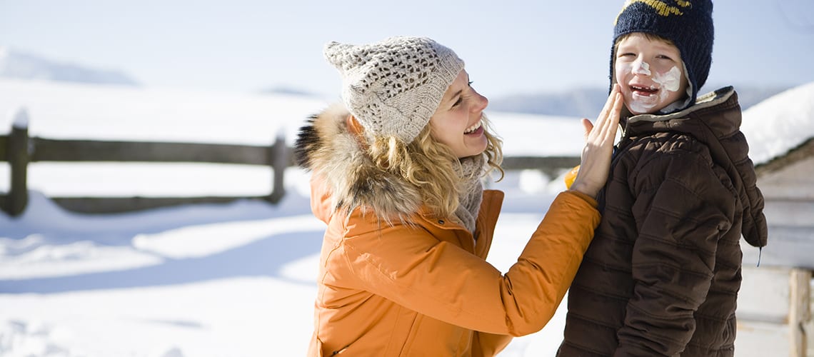 mère-mets-crème-solaire-à-son-fils-Neige