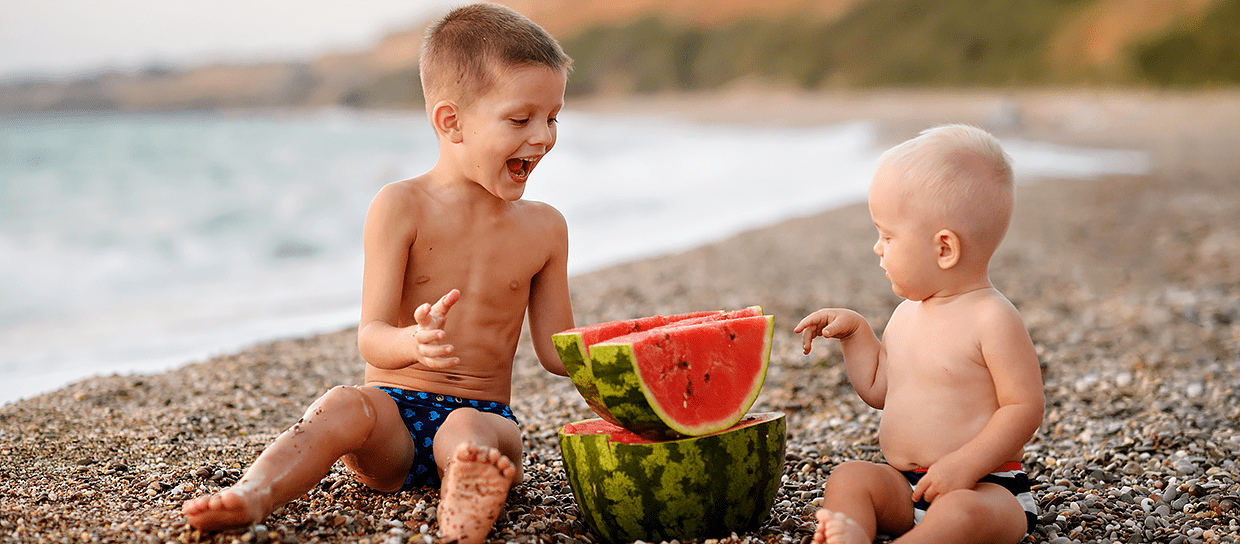Children eat a watermelon on the beach