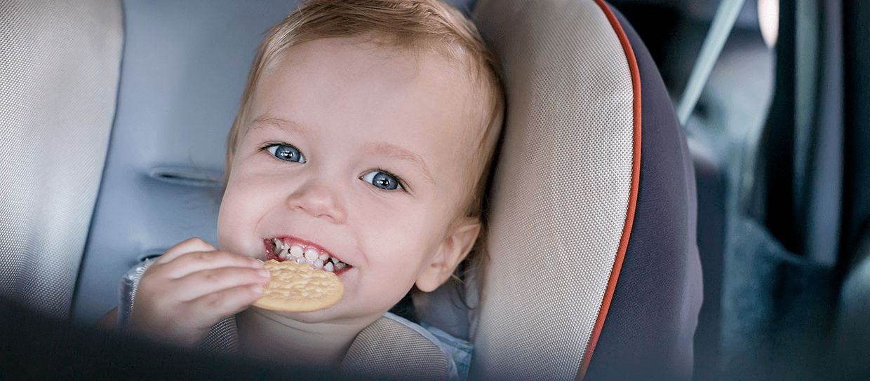 Baby eating a cake in the car